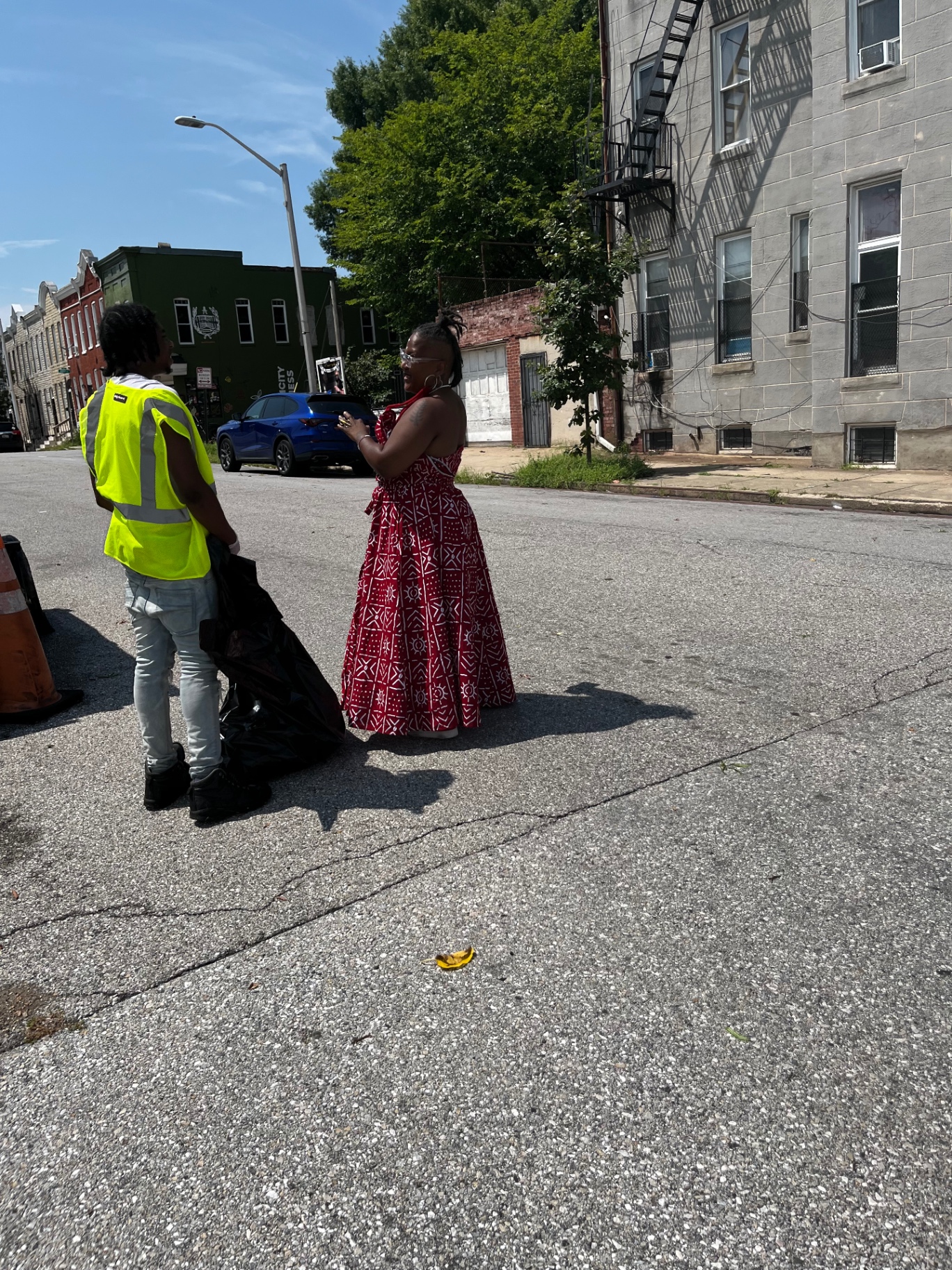 Two people connecting on a neighborhood street, one wearing a safety vest